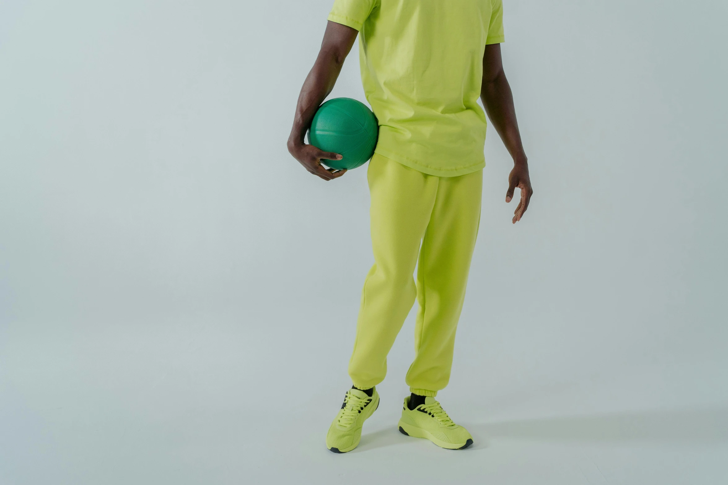 a man in a yellow shirt holding a green ball, trending on pexels, baggy pants, ((neon colors)), tracksuit, off - white collection