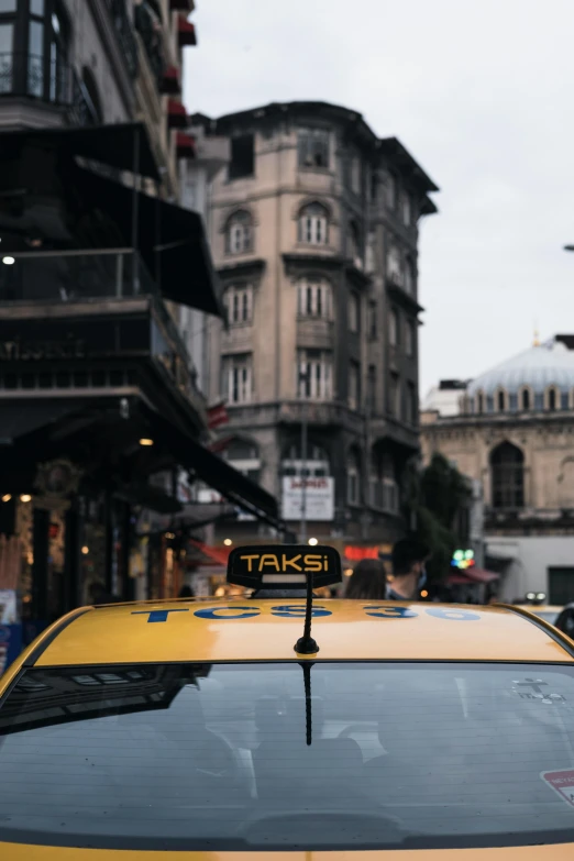 a yellow taxi cab driving down a city street, by Cafer Bater, pexels contest winner, fallout style istanbul, tail fin, 🚿🗝📝, front lit