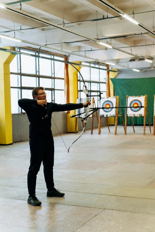 a man holding a bow and aiming at a target, a portrait, pexels contest winner, local gym, marina abramovic, panoramic shot, pittsburgh