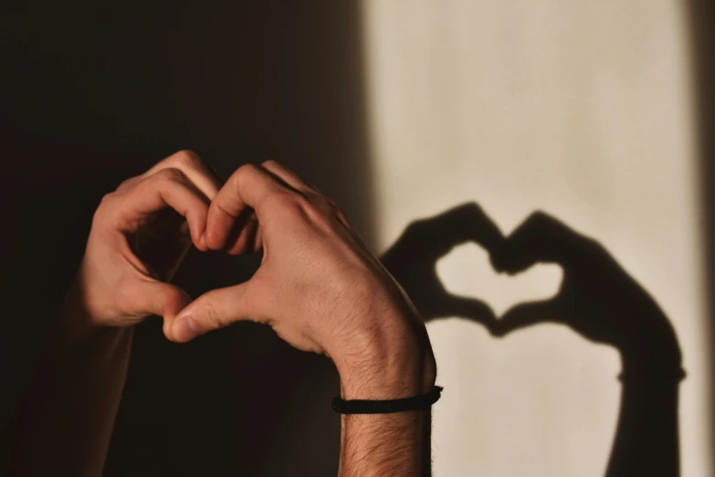 a person making a heart shape with their hands, trending on pexels, shadow of beard, fan favorite, profile image, lgbtq