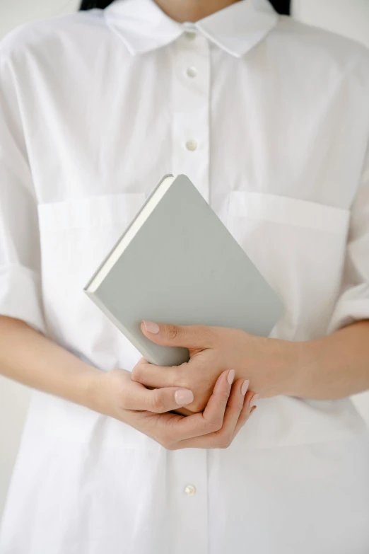 a woman in a white shirt holding a book, inspired by jeonseok lee, unsplash, light grey, white soft leather model, pale gray skin, detailed image