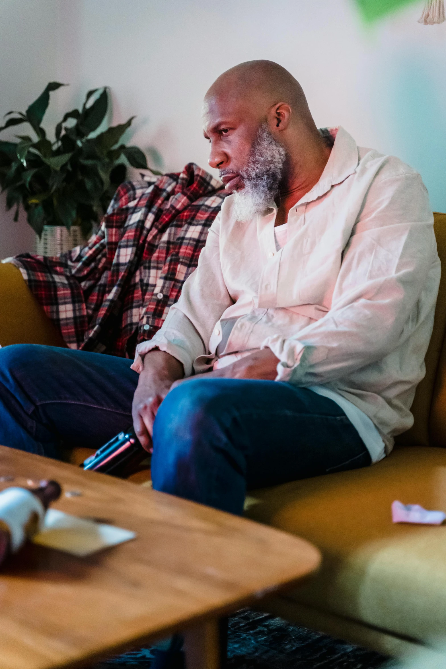 a man sitting on a couch in a living room, pexels, process art, concerned expression, riyahd cassiem, absent father, bald man