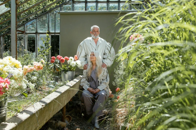 a man and a woman sitting on a bench in a garden, a portrait, by Harriet Zeitlin, pexels contest winner, renaissance, in bloom greenhouse, wearing long silver robes, herman nitsch and herman nitsch, grey