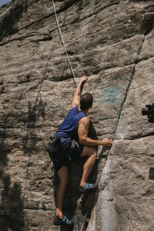 a man climbing up the side of a rock, by Leo Michelson, unsplash, arabesque, on the bow, action shots, texture, taken in the late 2010s