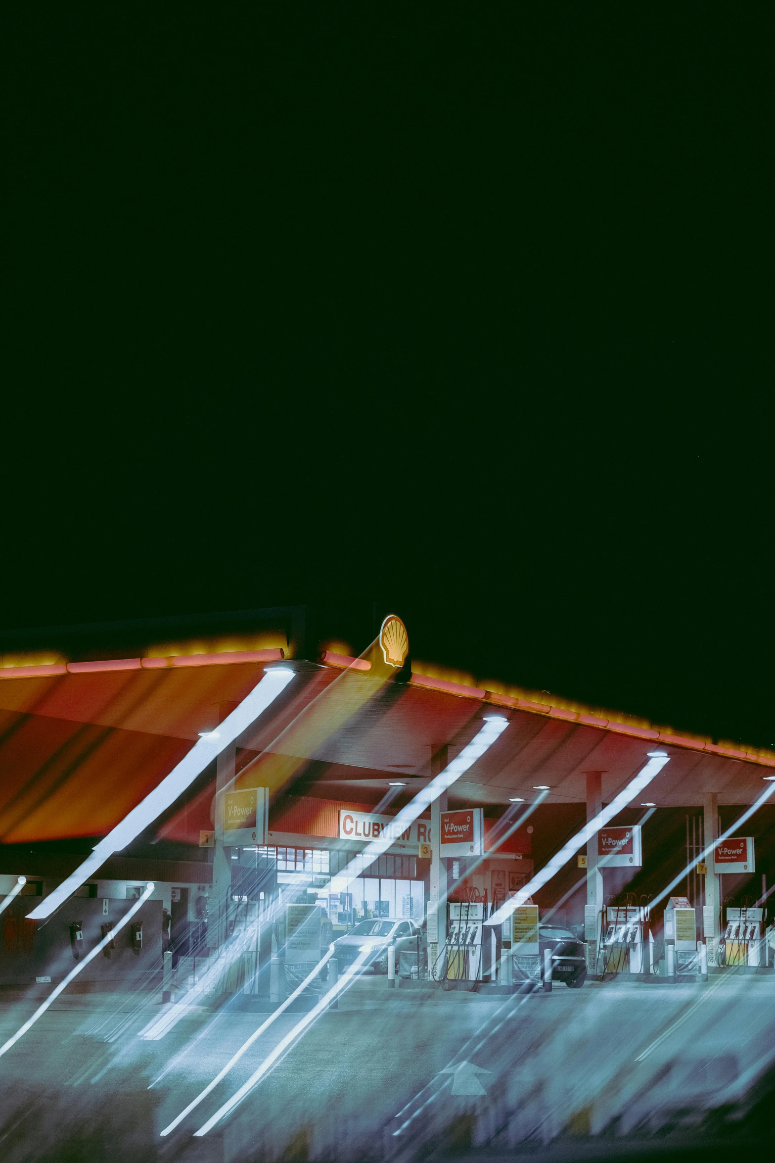 a blurry photo of a gas station at night, an album cover, inspired by Andreas Gursky, conceptual art, stadium, orange roof, color negative, color image