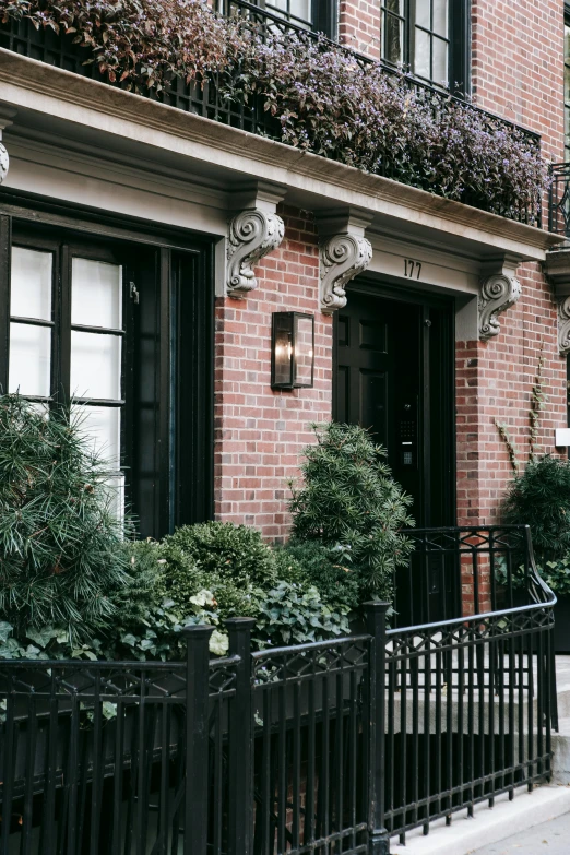 a red fire hydrant sitting in front of a brick building, by Nina Hamnett, unsplash, art nouveau, apartment with black walls, bushes, new york back street, architectural digest