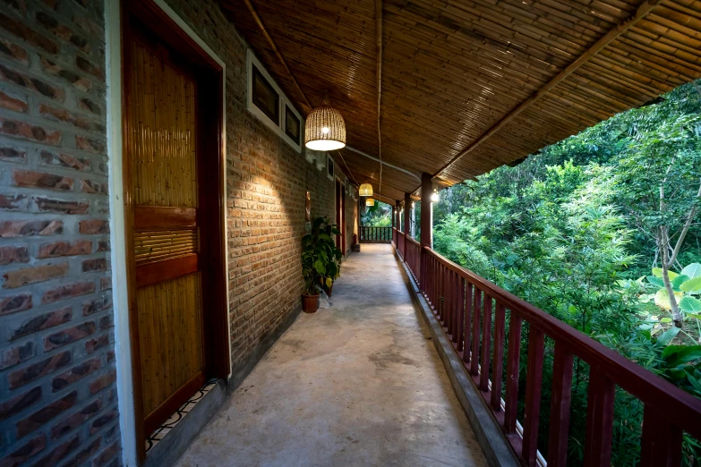 a long walkway with a lamp hanging from the ceiling, inspired by Huang Guangjian, unsplash, cottages, in the background is lush jungle, balcony, profile image