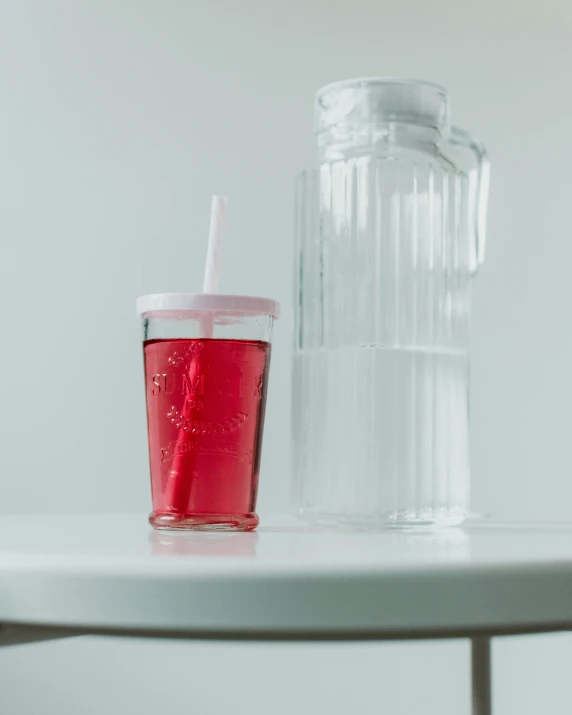 a red drink sitting on top of a white table, by Nina Hamnett, unsplash, dau-al-set, pink axolotl in a bucket, detailed product shot, translucent, family friendly