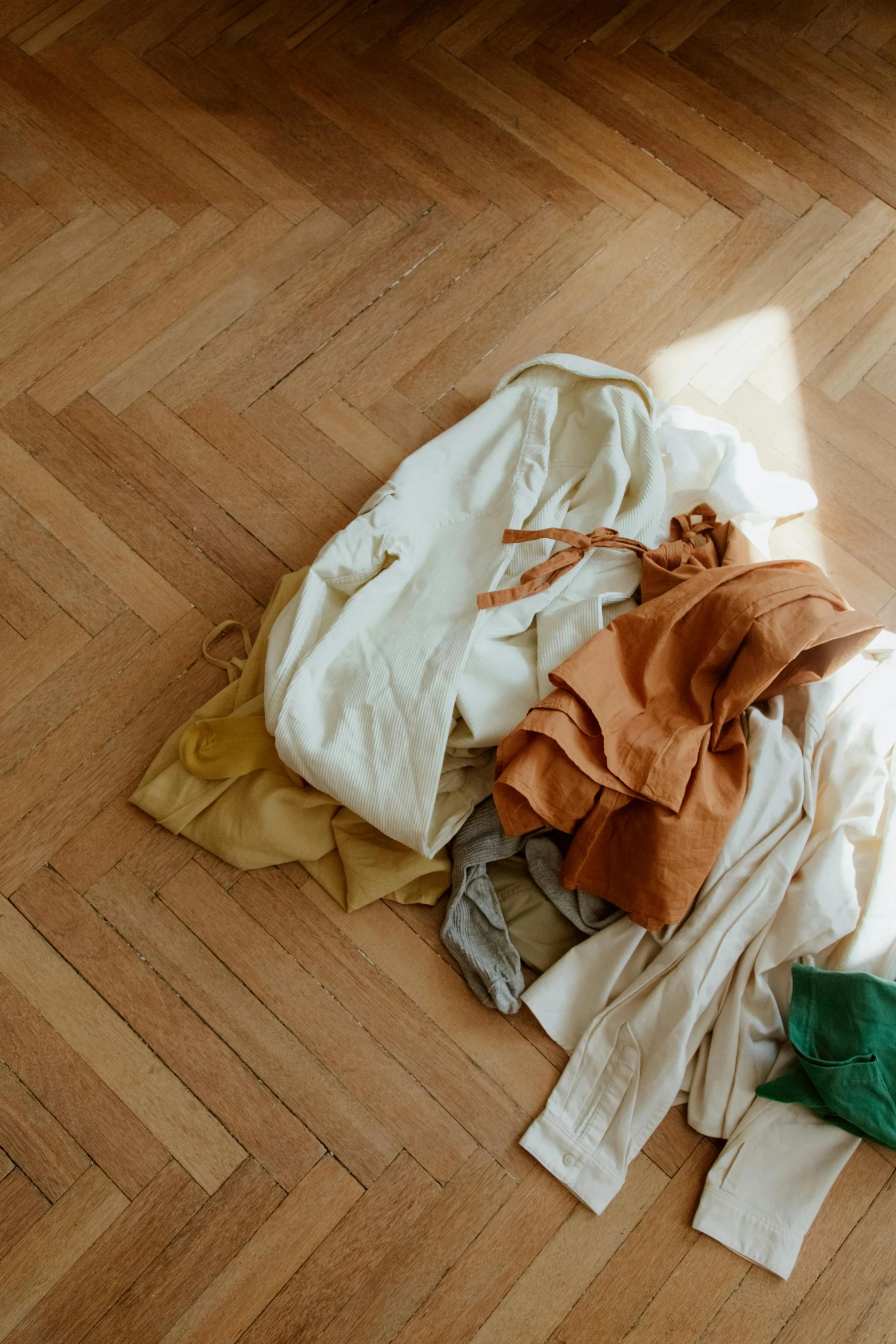 a pile of clothes sitting on top of a wooden floor, by Nina Hamnett, trending on unsplash, renaissance, brown and cream color scheme, bows, ochre, 5 colors