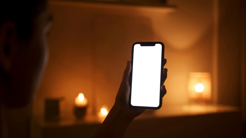 a person holding up a cell phone with a white screen, candles, serene lighting, no lighting, rectangle