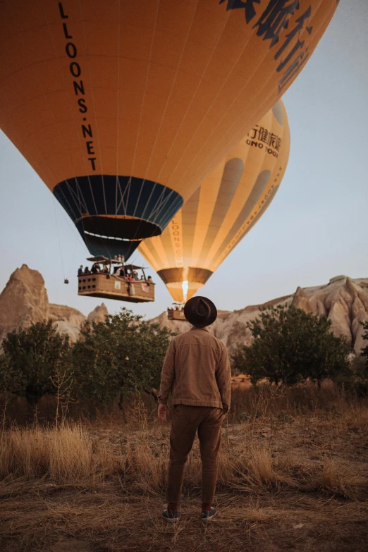 a man standing in front of a hot air balloon, by irakli nadar, unsplash contest winner, instagram story, ochre, rocket launching, turkey