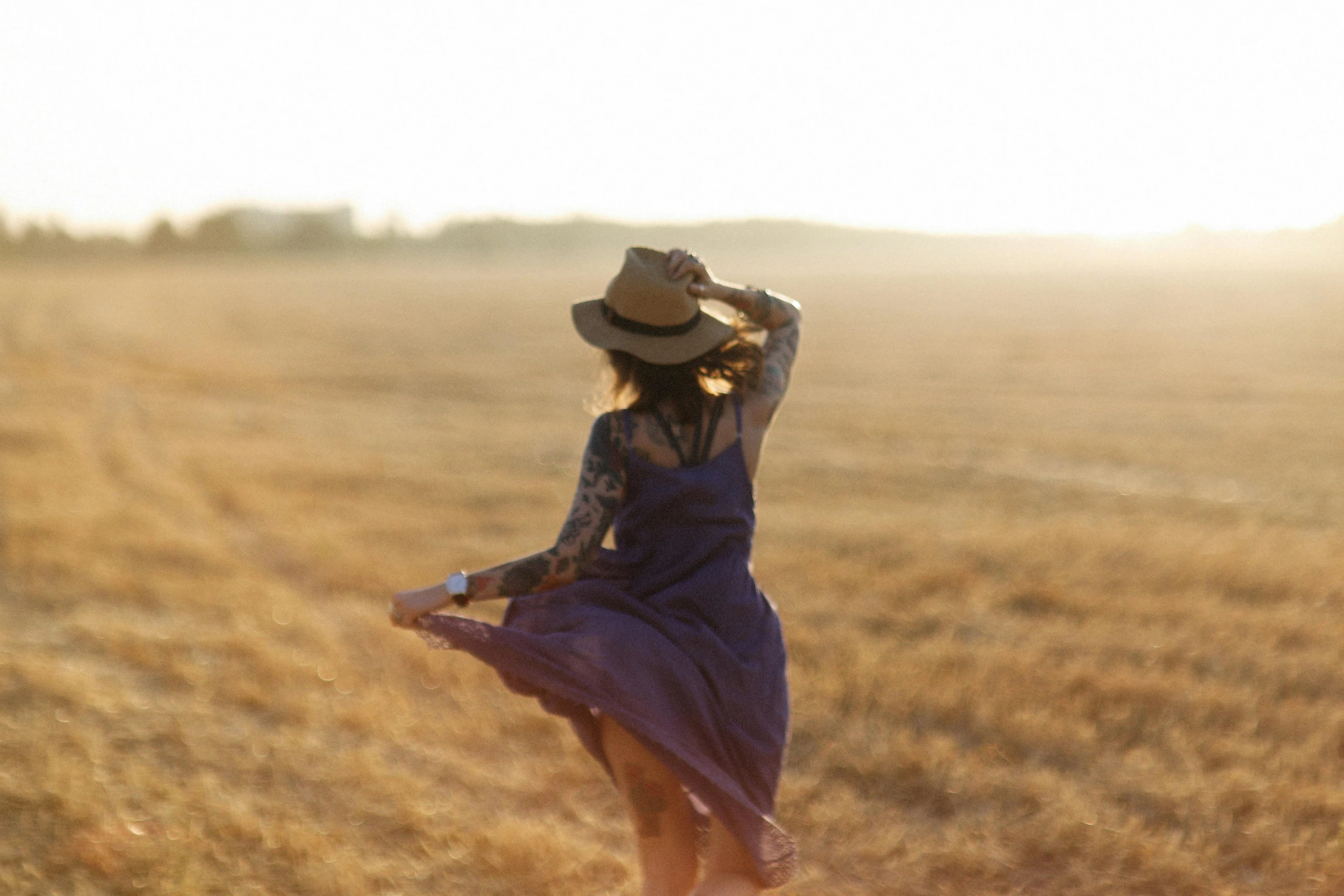 a woman in a dress and hat standing in a field, pexels contest winner, symbolism, dancing, working out in the field, fading off into the distance, end of the day