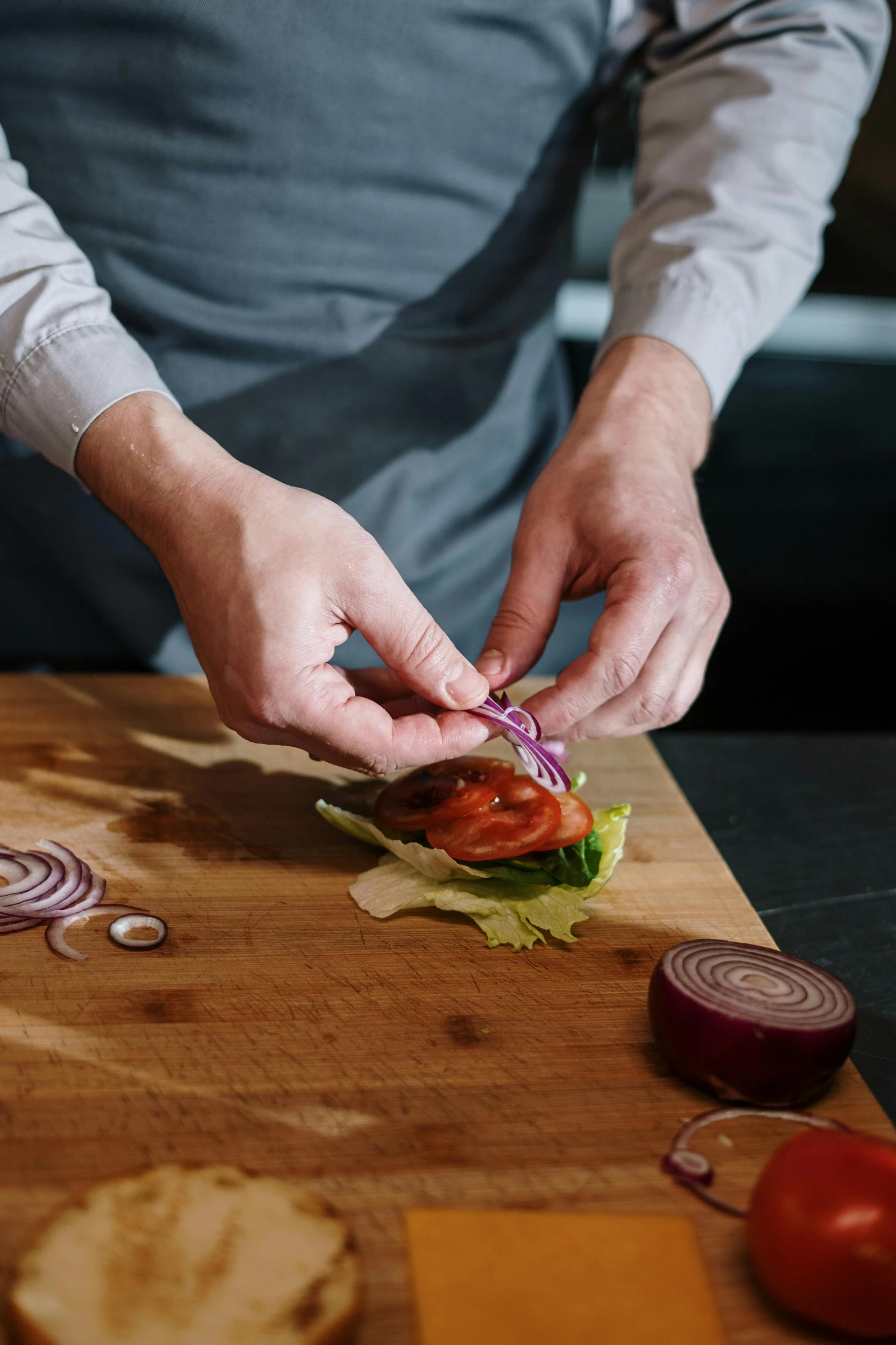 a person preparing a sandwich on a cutting board, onion, chefs table, paul barson, product introduction photo