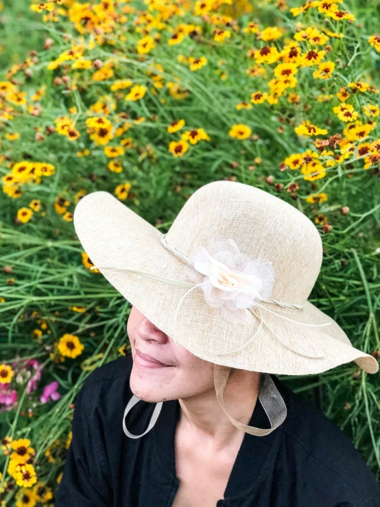 a woman laying down in a field of flowers, by Ellen Gallagher, white straw flat brimmed hat, profile picture, ribbon, in a cottagecore flower garden