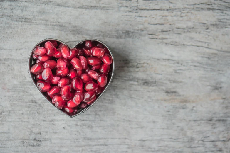 a heart shaped container filled with pomegranates, a photo, pexels, beans, jen atkin, magnesium, can