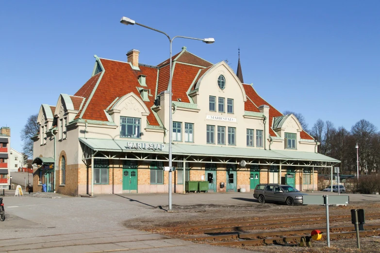 a train station with cars parked in front of it, inspired by Wilhelm Marstrand, art nouveau, norrlandsskog, green, square, brown