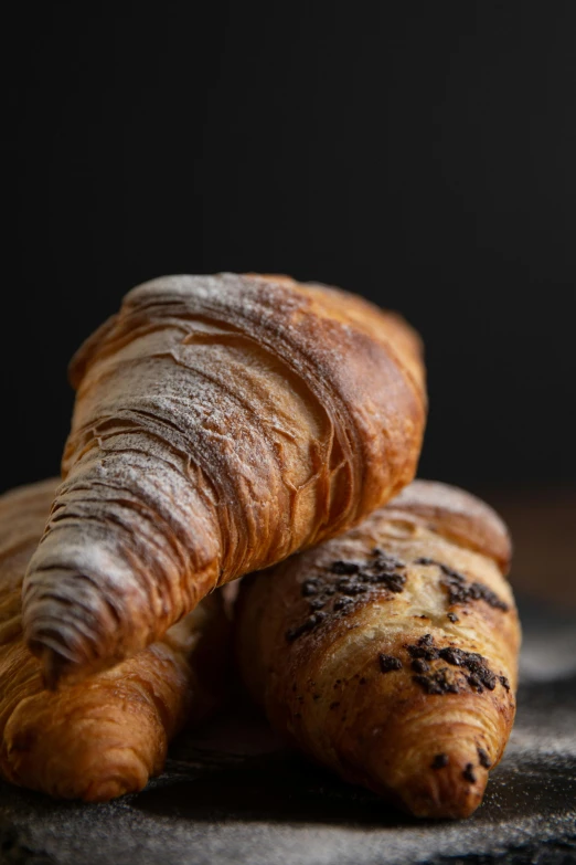 a couple of croissants sitting on top of a table, a portrait, by Carlo Martini, unsplash, low detail, thumbnail, bakery, high detail photograph