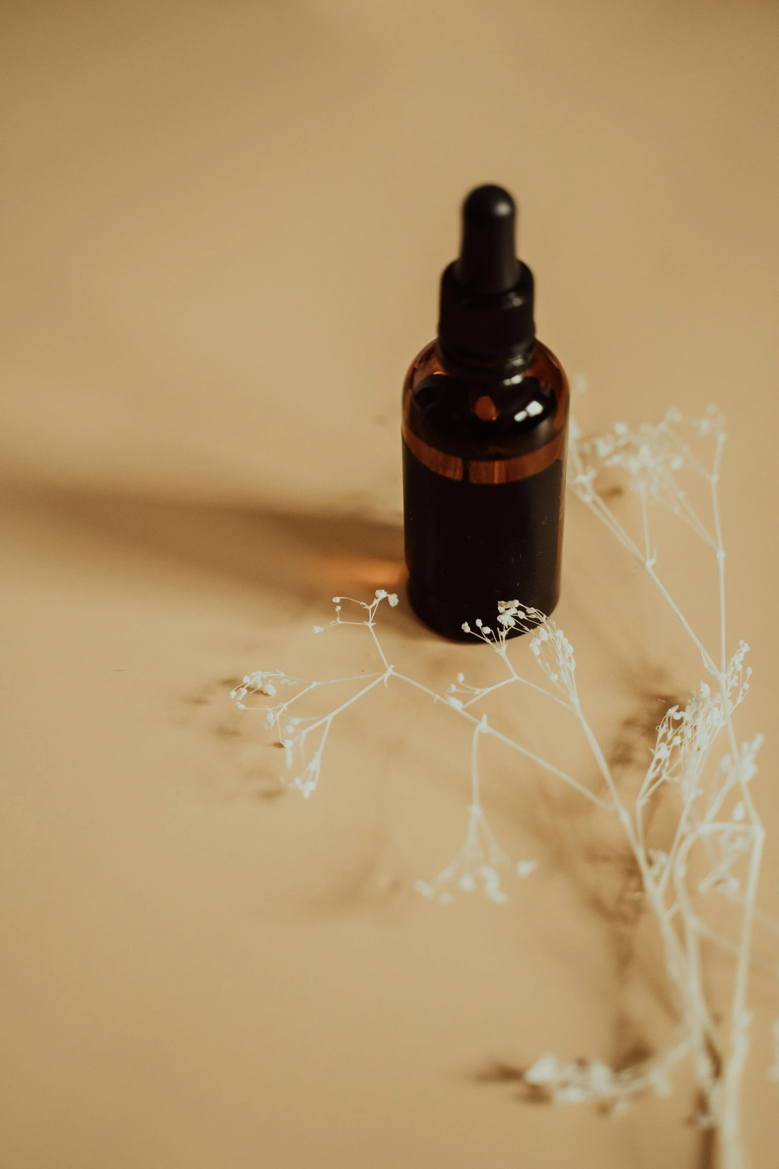 a bottle of essential oil sitting on a table, by Andries Stock, unsplash, aestheticism, black fine lines on warm brown, skin care, background image, made of wax and oil