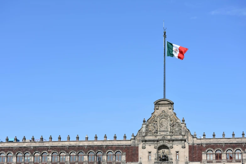 a large building with a flag on top of it, inspired by Germán Londoño, pexels contest winner, square, mexico city, clear blue skies, 2025