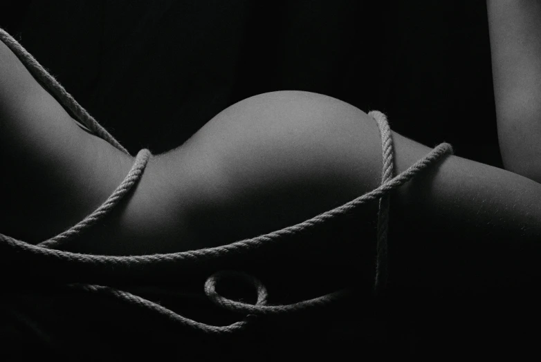 a black and white photo of a woman tied up, inspired by Robert Mapplethorpe, unsplash, shapely derriere, rope, album cover, making love
