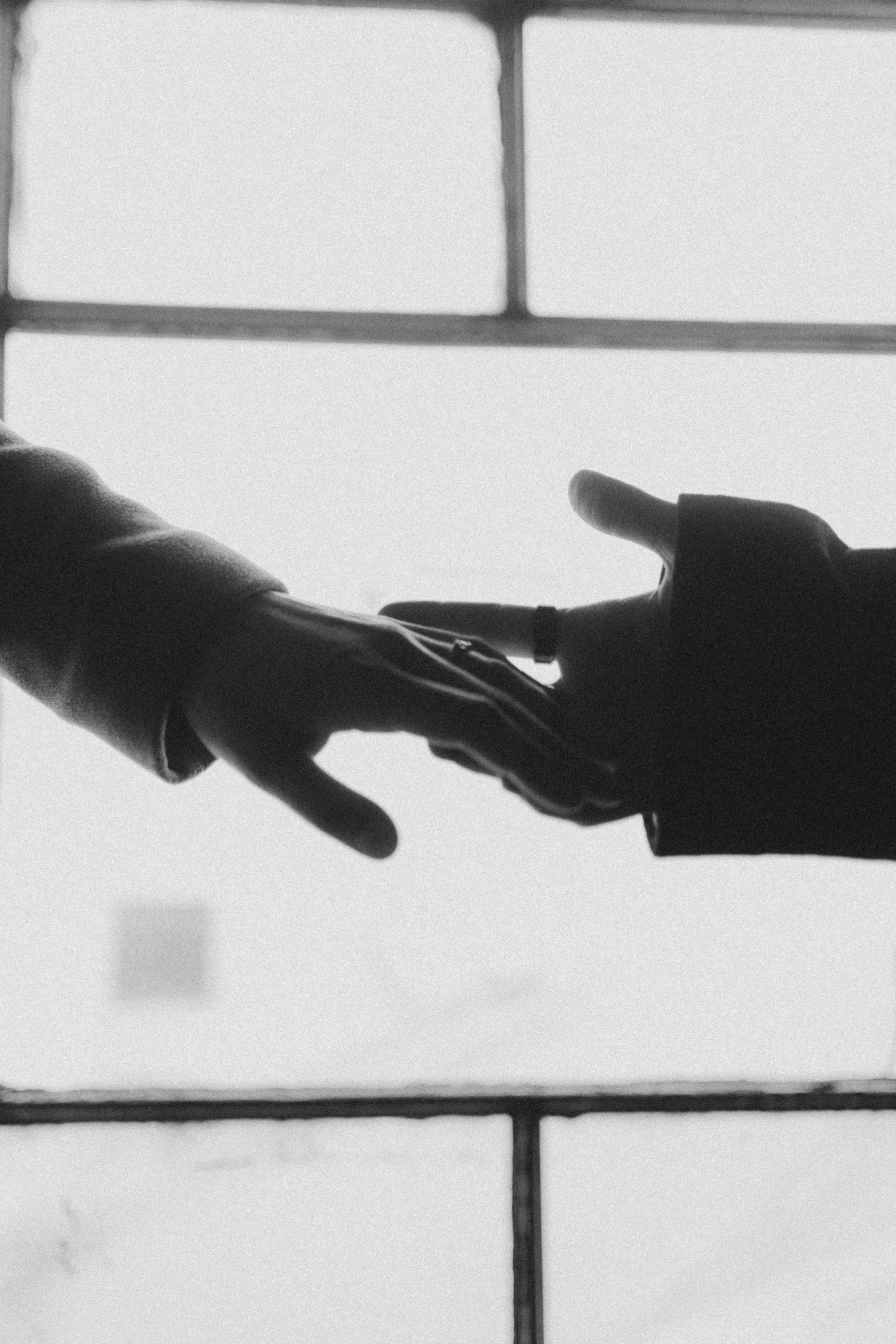 a black and white photo of two hands reaching out of a window, in meeting together, ffffound, lovers, siluette