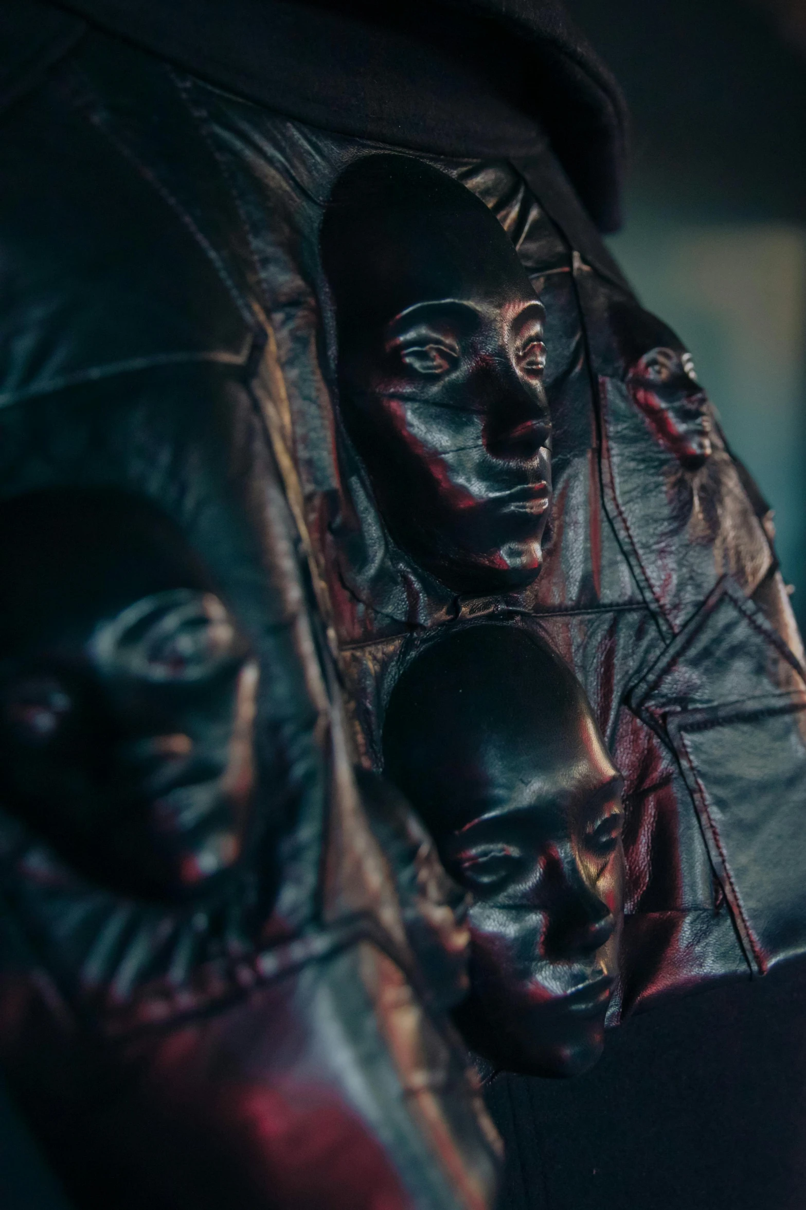 a close up of a leather jacket with masks on it, an album cover, inspired by Nicola Samori, new sculpture, each faces precisely define, ( ( dark skin ) ), wearing hoods, oily high relief