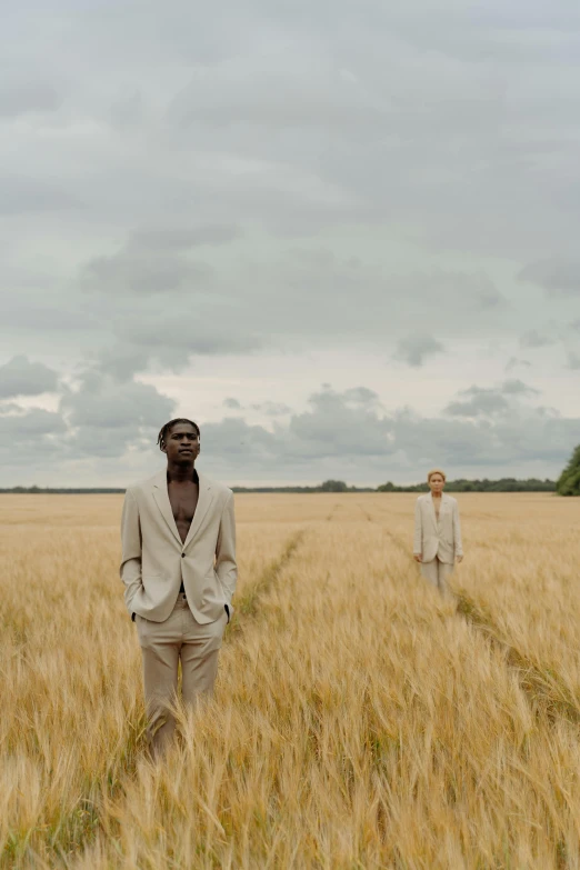 two men standing in a field of wheat, an album cover, inspired by Barthélemy Menn, movie still frame, gold suit, ignant, ! movie scene