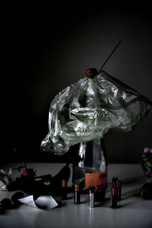 a black cat sitting on top of a table next to a bottle, a still life, unsplash, conceptual art, cracked plastic wrap, bat wings, garbage plastic, high quality photo