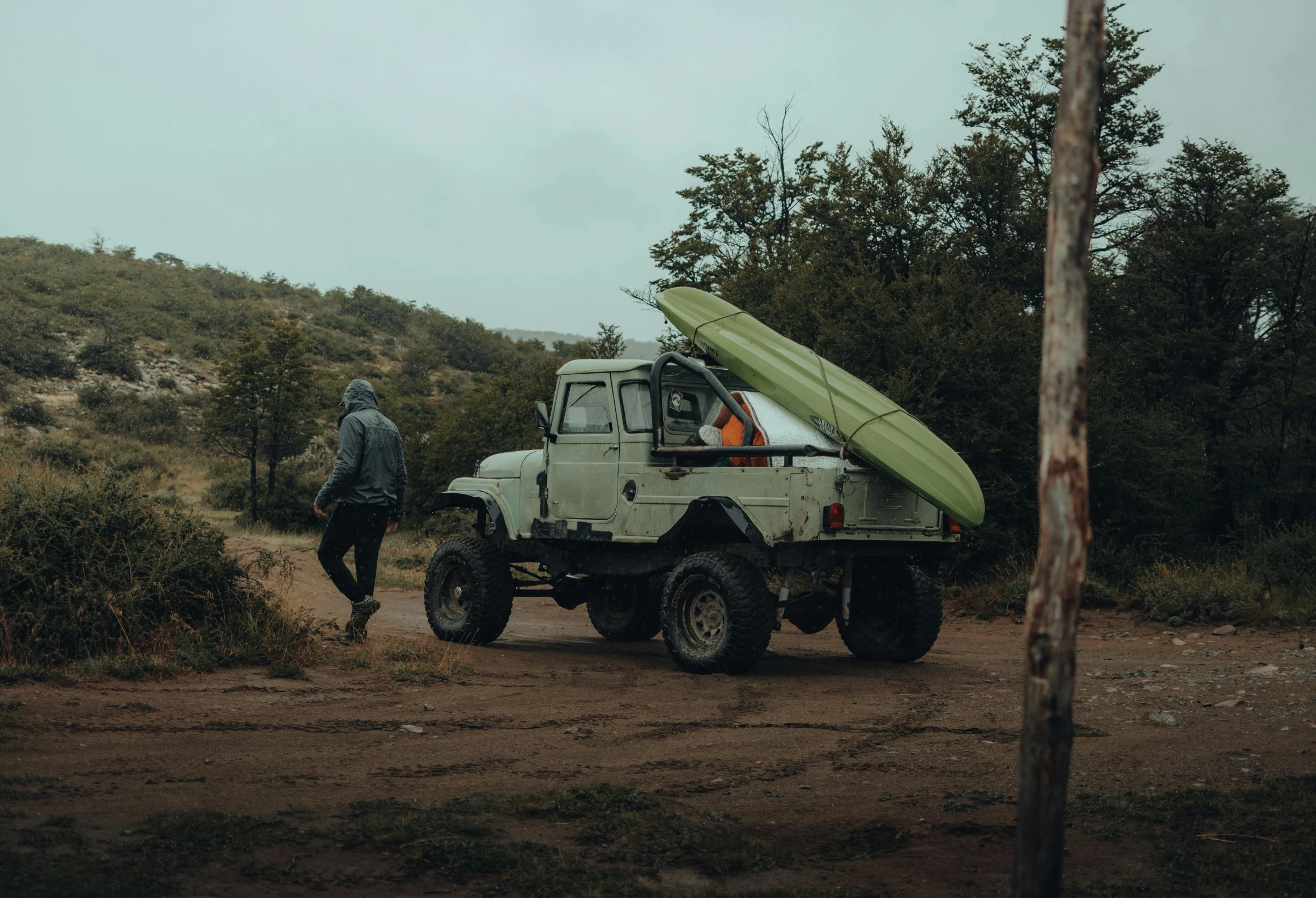 a man standing next to a truck with a surfboard on top of it, a picture, by Elsa Bleda, pexels contest winner, on a kayak in a forest, moskvich, rugged details, 2 people