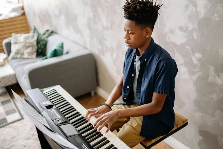 a young man sitting at a keyboard in a living room, pexels, american barbizon school, black teenage boy, musical instrument, avatar image, sydney hanson