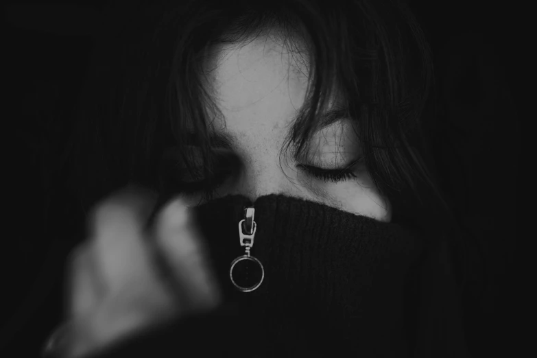 a black and white photo of a woman covering her face with a zipper, by Emma Andijewska, pexels contest winner, wearing a black sweater, piercing eye, very sad, girl with dark brown hair