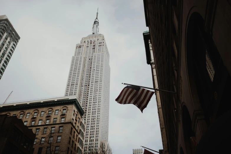 an american flag flying in front of a tall building, a photo, by Emma Andijewska, unsplash contest winner, empire state building, whitewashed buildings, brown, slide show