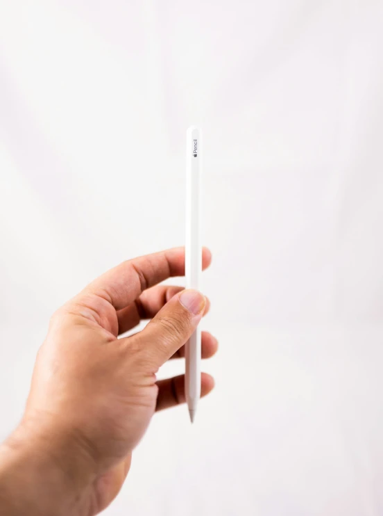 a person holding a white pencil in their hand, an album cover, by Robbie Trevino, unsplash, side-view. highly detailed, ipad pro, glossy white metal, tall thin