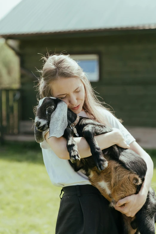 a woman holding a baby goat in her arms, unsplash, teenage girl, aged 13, beautiful surroundings, premium