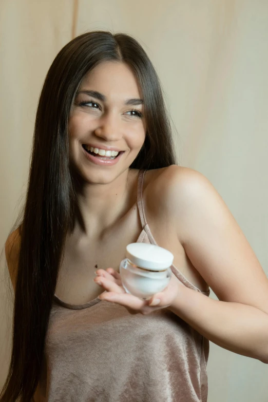 a beautiful young woman holding a cup of coffee, a portrait, by Juan O'Gorman, skincare, holding a bottle of arak, cream, zoomed in