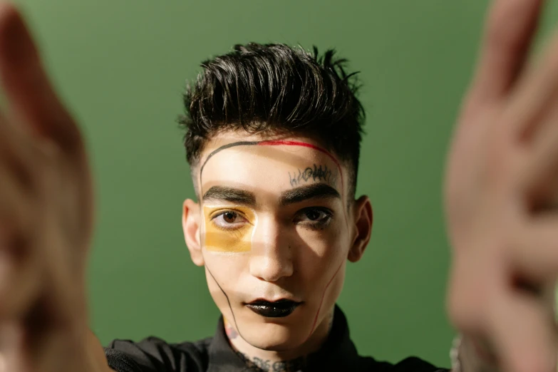 a close up of a person with a painted face, an album cover, inspired by Taro Yamamoto, trending on pexels, androgynous male, model posing, thawan duchanee, zayn malik