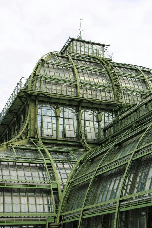 a large green building with lots of windows, inspired by Luigi Kasimir, art nouveau, greenhouse, up-close, parapets, wrought iron