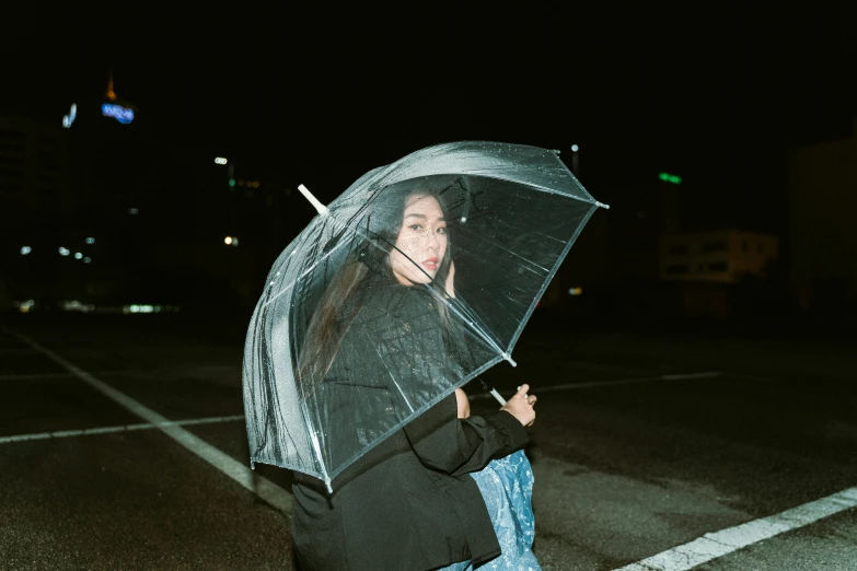 a woman standing in the middle of a street holding a clear umbrella, inspired by Elsa Bleda, hong june hyung, in front of a black background, in style of ren hang, ulzzang
