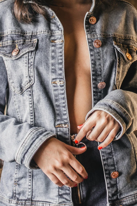 a woman in a denim jacket holding a camera, an album cover, inspired by Elsa Bleda, trending on pexels, figuration libre, her belly button is exposed, risque fashion, unclipped fingernails, sexy outfit