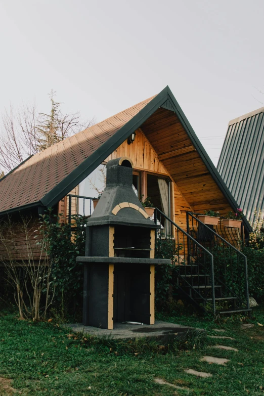 a couple of houses sitting on top of a lush green field, outdoor campfire pit, stood outside a wooden cabin, chilean, barbecue