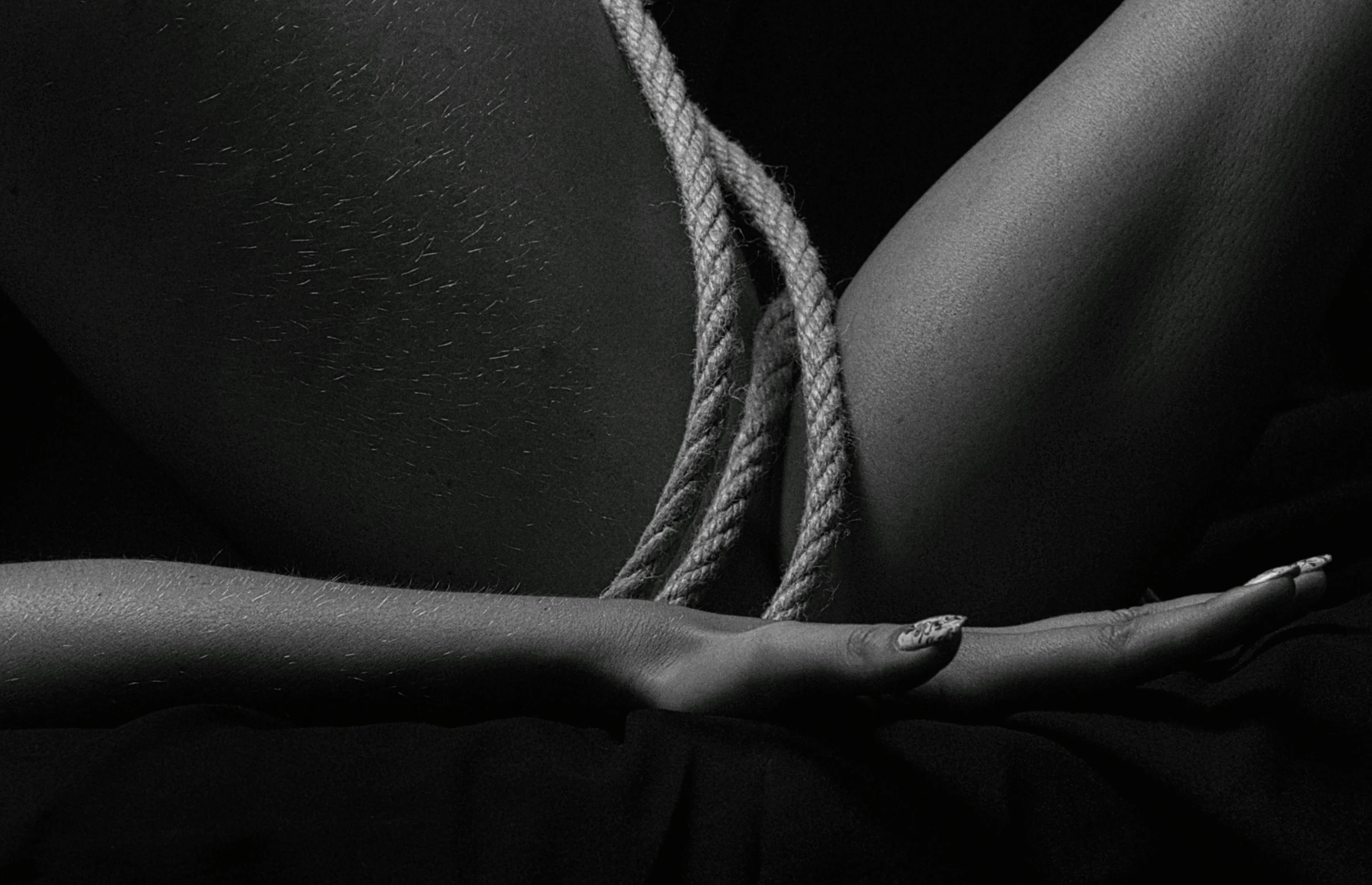 a woman is tied up with a rope, a black and white photo, by Adam Marczyński, unsplash, conceptual art, deep black skin, thighs close up, done in the style of caravaggio, teaser