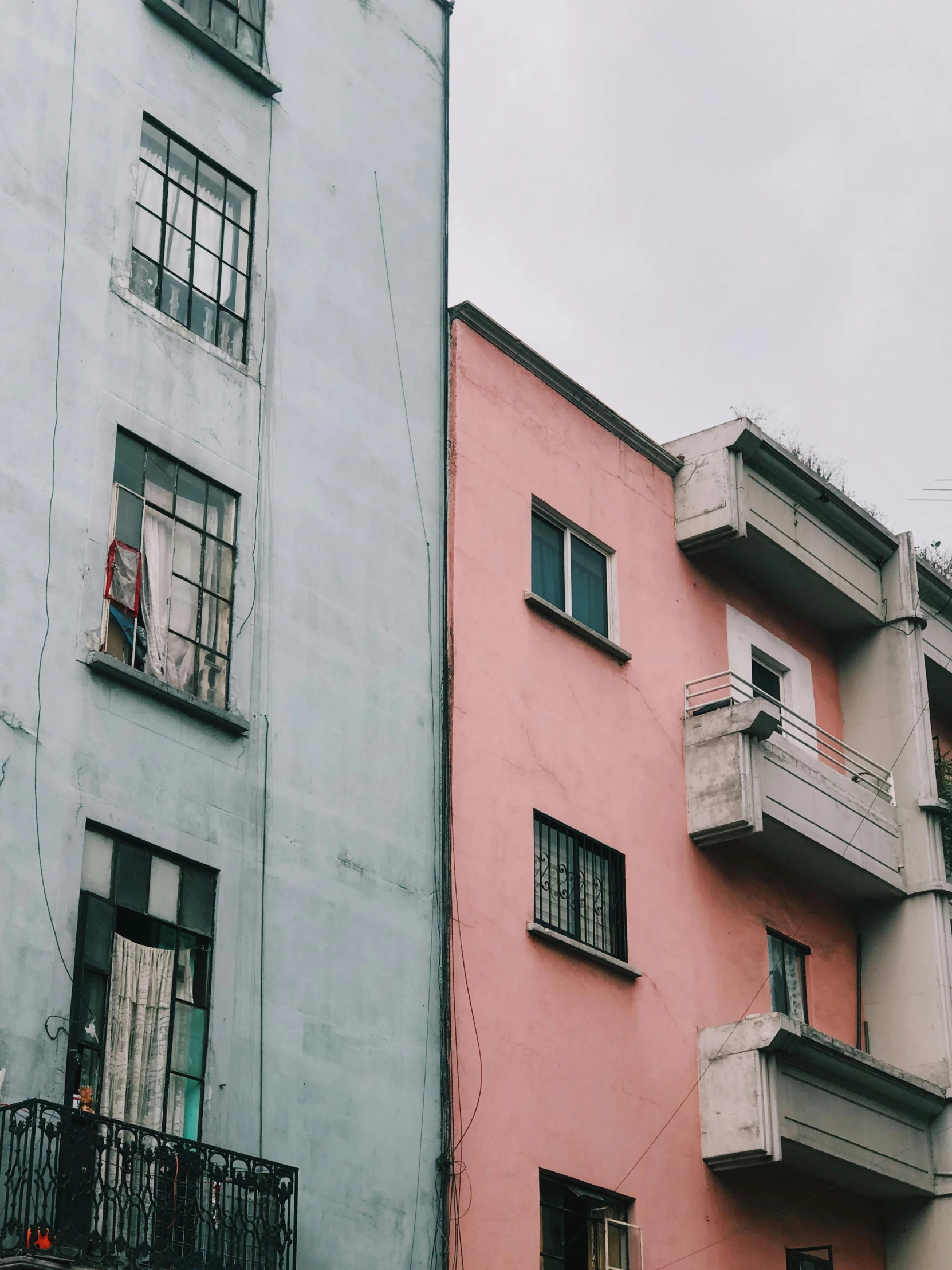 a couple of buildings that are next to each other, by Lucia Peka, unsplash contest winner, modernism, dull colours, the walls are pink, old buildings, instagram story