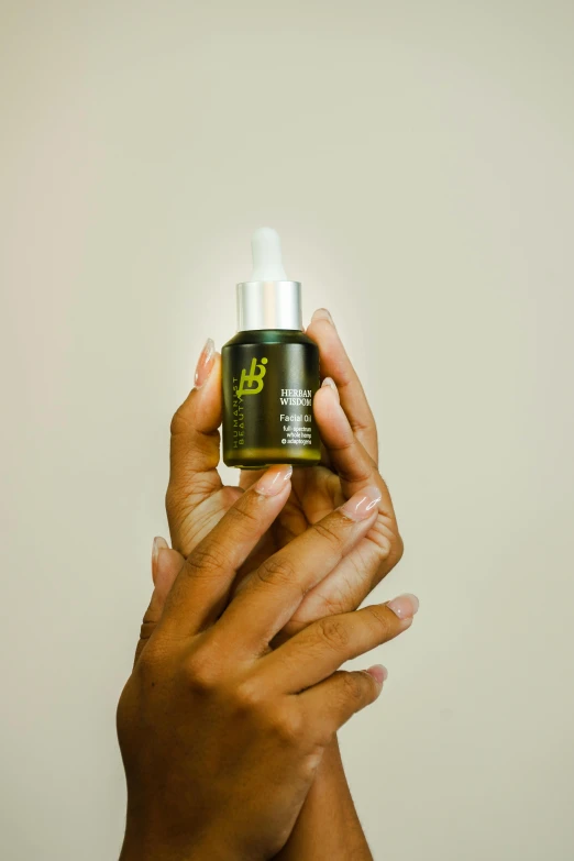 a close up of a person holding a bottle of liquid, natural complexion, transplanted hand to head, oils, ebony