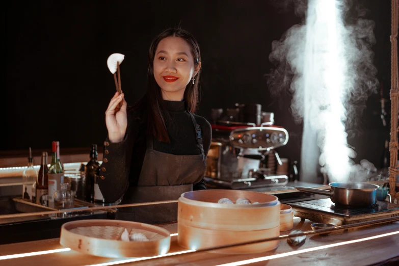 a woman standing in a kitchen holding a spatula, a portrait, inspired by Tan Ting-pho, pexels contest winner, mingei, in front of smoke behind, steamed buns, avatar image, at the counter