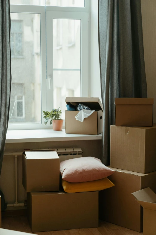 a room filled with boxes and a window, next to a window, home setting, bay area, individual