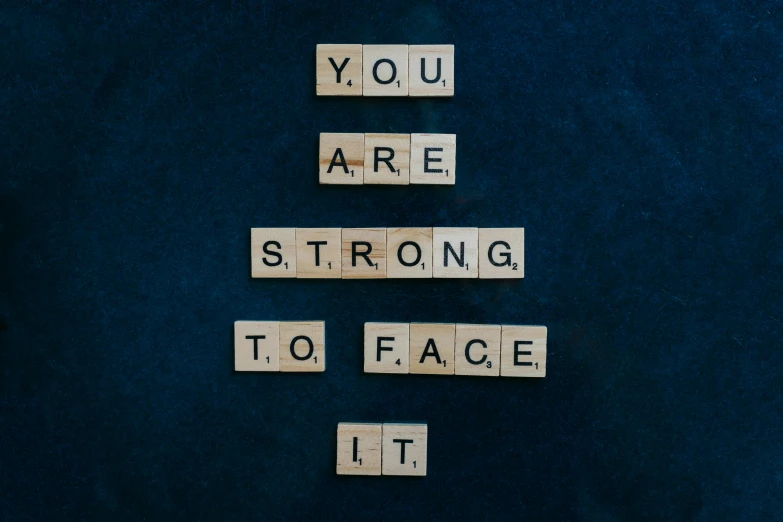 a scrabble that says you are strong to face it, a picture, by Julia Pishtar, trending on pexels, square facial structure, navy, body and face, effect
