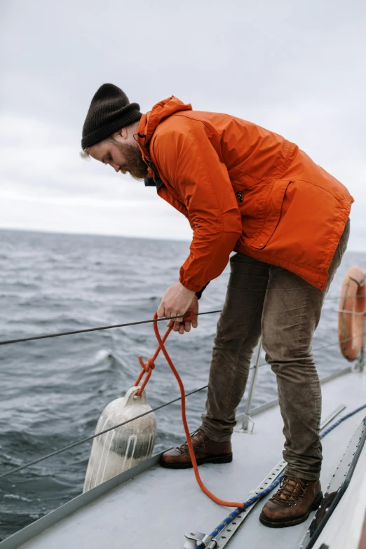 a man in an orange jacket on a boat, pexels contest winner, pouring, utilitarian, lightly dressed, iceland