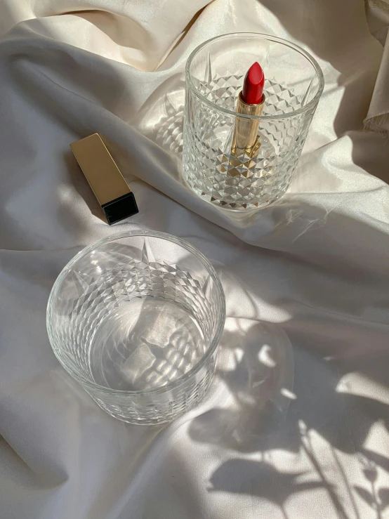 a red lipstick sitting next to a glass of water, crystal cubism, taken on iphone 14 pro, inside a glass jar, flatlay, detailed product image