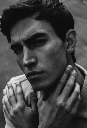 a black and white photo of a man with his hand on his chest, a black and white photo, inspired by Peter Lindbergh, pexels contest winner, hyperrealism, square masculine jaw, robert sheehan, in style of petra collins, high cheekbones