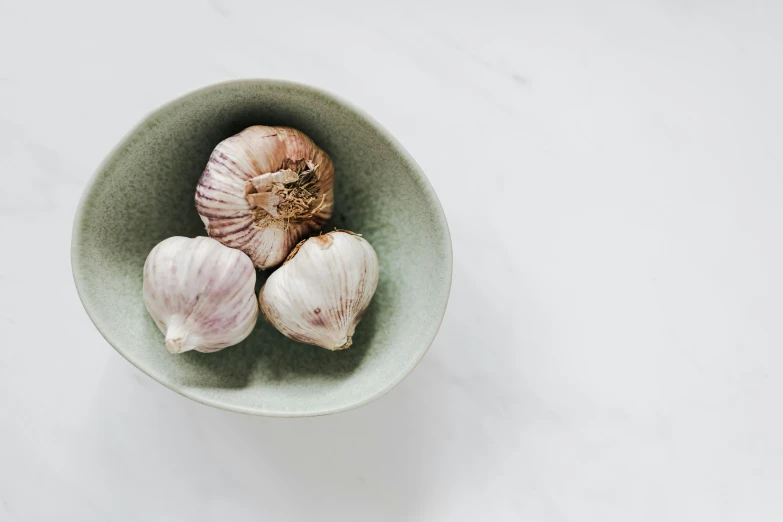 three bulbs of garlic in a green bowl, trending on unsplash, made of carrara marble, grey, local foods, 3 - piece